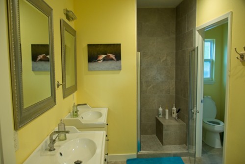 Upstairs bathroom with tiled shower, two sinks, toliet.