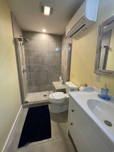 view of downstairs bathroom with sink, shower, toliet, room heating and cooling.